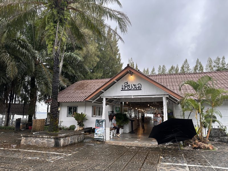 หน้าร้านอาคารหน้าจั่วสีขาว มีป้ายชื่อเคียงเล และต้นมะพร้าว