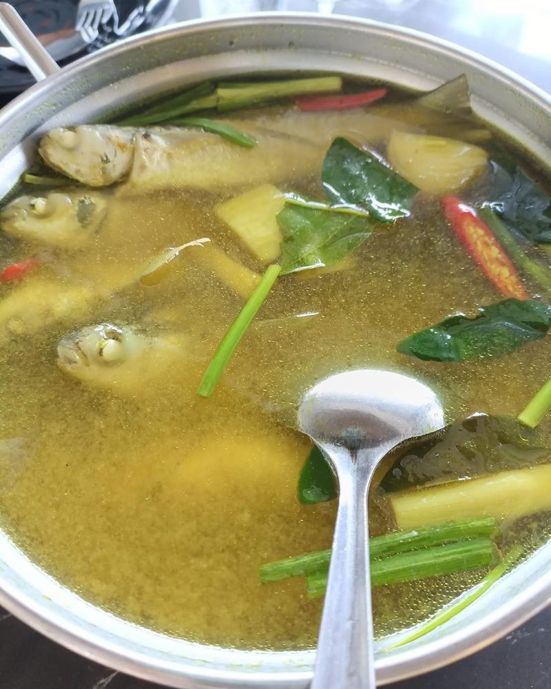 หม้อแกงน้ำสีเหลืองใส่ปลาและผัก